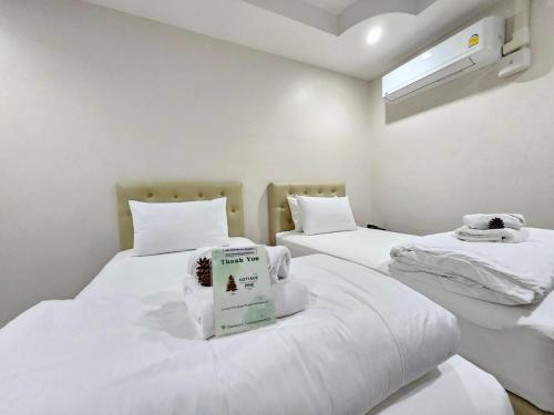 a room with two beds with white sheets and a window at CottagePine Rayong Resort&Cafe in Ban Ko Kloi