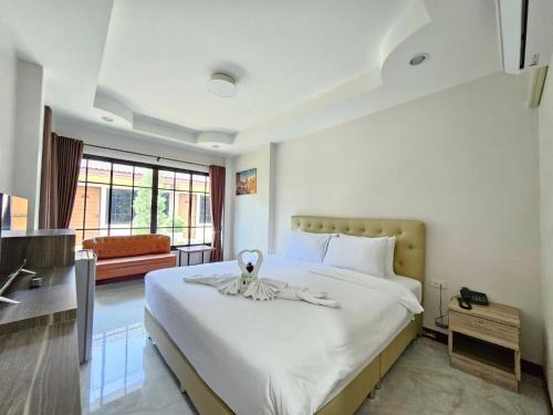 a bedroom with a large white bed with a towel on it at CottagePine Rayong Resort&Cafe in Ban Ko Kloi