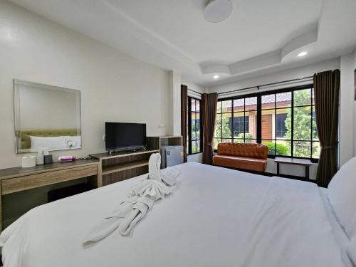 a bedroom with a large white bed and a television at CottagePine Rayong Resort&Cafe in Ban Ko Kloi