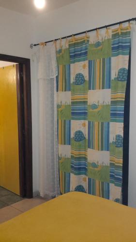 a bedroom with a yellow bed and a curtain at casa di campagna dal pozzo in Sorso
