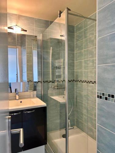 une salle de bain avec une douche en verre et un lavabo dans l'établissement Mettons les voiles - Appt vue mer avec loggia, à Bernières-sur-Mer
