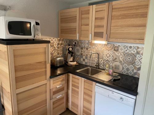 une petite cuisine avec un micro-ondes et un évier dans l'établissement Appt hyper centre Saint-Lary-Soulan village avec jardin, à Saint-Lary-Soulan