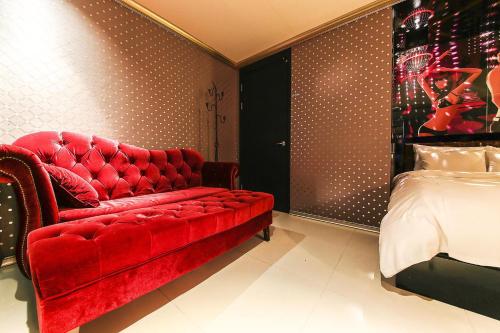 a red couch and a bed in a room at The Oreun Echae Hotel in Jeju