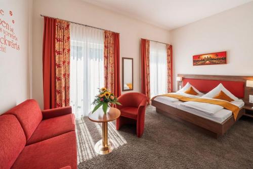 a bedroom with a red bed and a red couch at Hotel Donaublick in Scheer