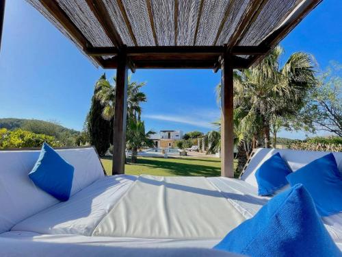 a white bed with blue pillows sitting under a roof at Holiday Home San Jose near Stunning Beaches in Sant Josep