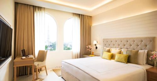 a bedroom with a bed and a desk and a window at Taj Ganges Varanasi in Varanasi