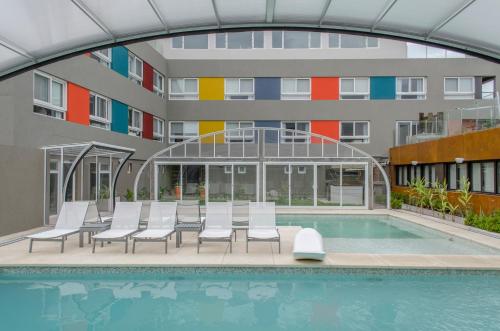 a swimming pool with chairs and a building at Almarena Apart & Hotel Boutique in Costa del Este