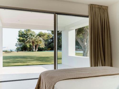 a bedroom with a large window looking out onto a golf course at Finca in Ibiza with Sea Views & Infinity Pool in Sant Francesc de s'Estany