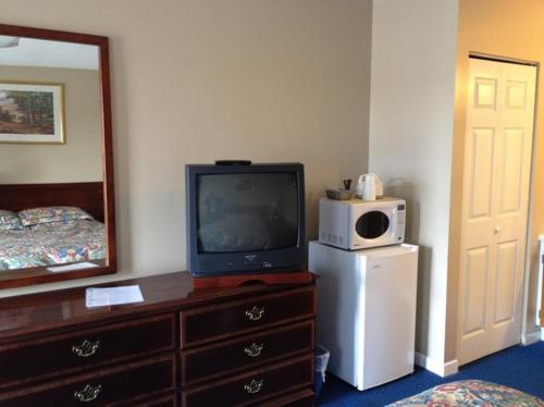 a room with a tv on a dresser with a microwave at Lotus Motel in Cobourg