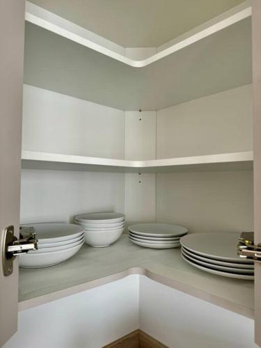 une cuisine avec des bols blancs et des assiettes sur une étagère dans l'établissement Studio moderne et tout équipé, proche du RER, Paris & aéroport d'Orly en 20 min, lit bébé sur demande, à Vitry-sur-Seine