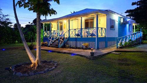 a blue and yellow house with a tree in the yard at Ketlina Village in Providencia