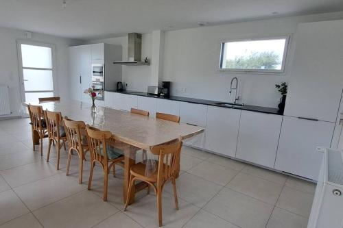 une grande cuisine avec une table et des chaises en bois dans l'établissement MoLiMa, maison de bord de mer, 12à14 personnes, à Loctudy