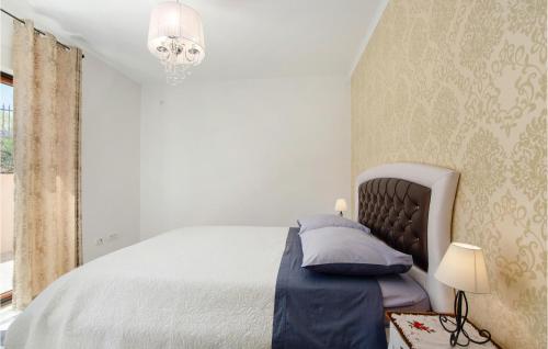 a white bedroom with a bed and a chandelier at Stunning Home In Dugopolje With Sauna in Dugopolje
