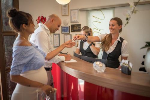 a group of people standing around a reception counter at Hotel Donaublick in Scheer