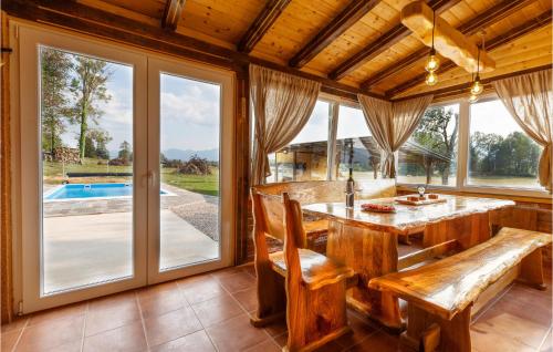 a dining room with a table and chairs and windows at Lovely Home In Smiljan With Sauna in Smiljan