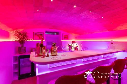 a pink room with a counter and some chairs at Villa De Los Leones in heart of Sitges by Beach and Town with A/C and Games in Sitges