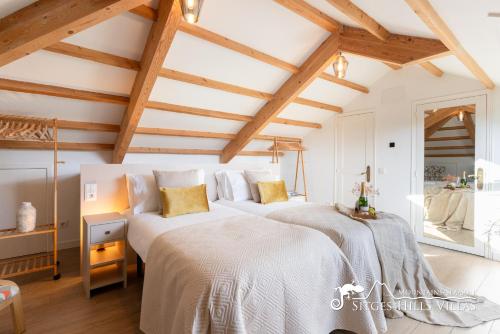 two beds in a room with wooden ceilings at Villa De Los Leones in heart of Sitges by Beach and Town with A/C and Games in Sitges