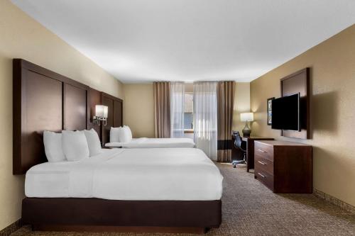 a hotel room with two beds and a flat screen tv at Comfort Inn & Suites Greeley in Greeley