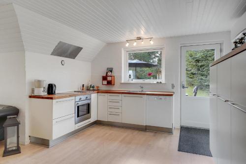 a kitchen with white cabinets and a window at BLÅBJERGGAARD - Hennebysvej 58 in Henne Strand