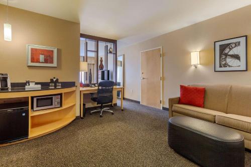 a living room with a couch and a desk with a computer at Cambria Hotel Ft Collins in Fort Collins