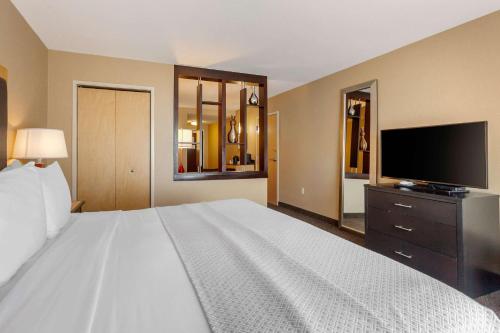a bedroom with a large white bed and a flat screen tv at Cambria Hotel Ft Collins in Fort Collins