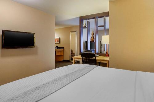 a bedroom with a bed and a desk and a television at Cambria Hotel Ft Collins in Fort Collins