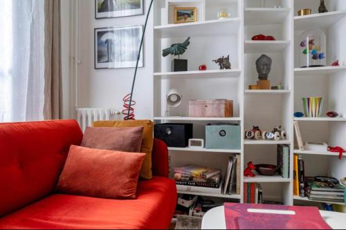 - un salon avec un canapé rouge et des étagères blanches dans l'établissement Charming quiet apartment near Montmartre, à Paris