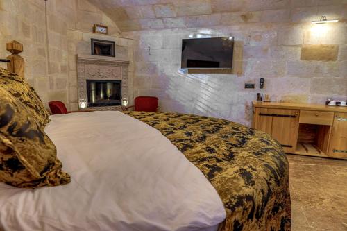 a bedroom with a large bed and a stone wall at Göreme Cave Suites in Goreme