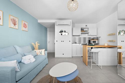 un salon avec un canapé bleu et une cuisine dans l'établissement Studio Amanda - Welkeys, à Nice