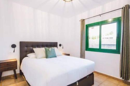 a bedroom with a large white bed and a window at Casa Roma in Puerto del Carmen