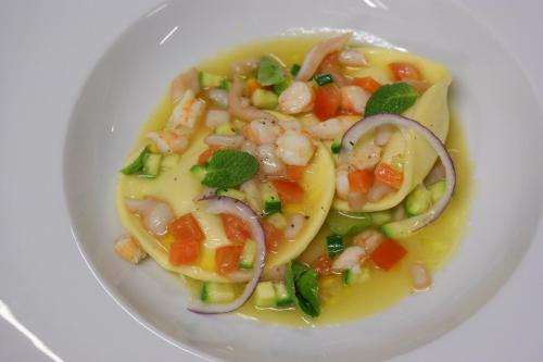 a white plate of food with shrimp and vegetables at Hotel Ristorante Fatur in Cisano Bergamasco