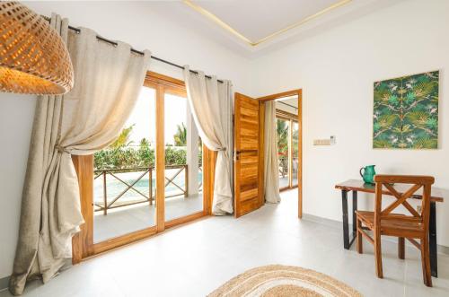 a living room with sliding glass doors and a table at Kamili Villas, Bwejuu, Zanzibar in Bwejuu