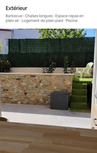 un mur en briques avec une télévision dans le jardin dans l'établissement T1 28m2 en RDC avec jardin et piscine, à Cabestany