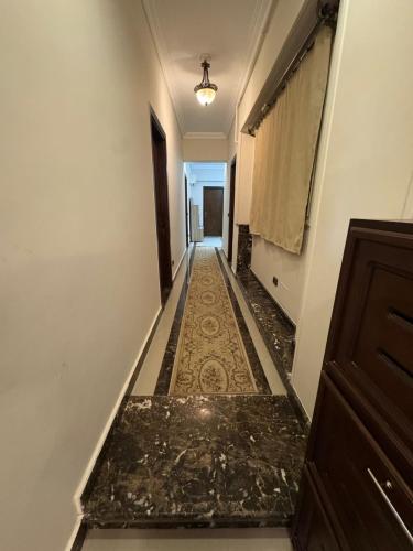 a long hallway with a tile floor and a hallway with a door at El Narges fully furnished apartment for rent new cairo in Cairo
