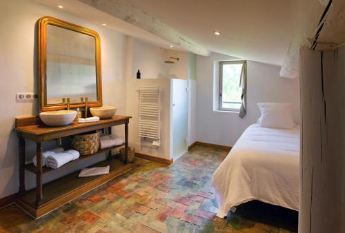 une chambre avec un lit et un grand miroir dans l'établissement Mas St Joseph, à Châteauneuf-Val-Saint-Donat