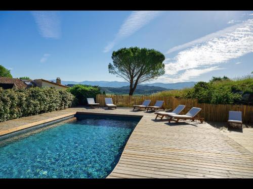 une piscine avec des chaises longues et une terrasse en bois dans l'établissement Mas St Joseph, à Châteauneuf-Val-Saint-Donat