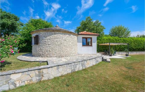 a small house in a garden with a stone wall at One-Bedroom Holiday Home In Zminj in Žminj