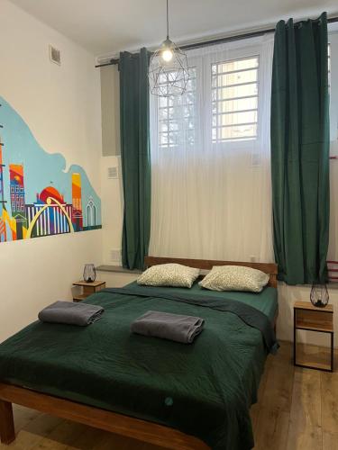 a bedroom with a bed with green sheets and a window at TomTom Hostel in Krakow