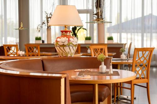 a dining room with tables and chairs and a lamp at Wyndham Garden Wismar in Wismar