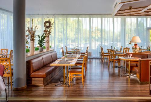 a restaurant with wooden tables and chairs and windows at Wyndham Garden Wismar in Wismar
