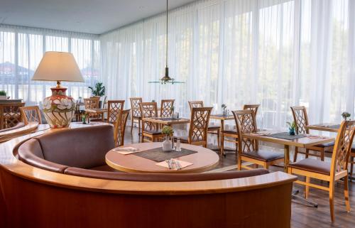 a dining room with tables and chairs and windows at Wyndham Garden Wismar in Wismar