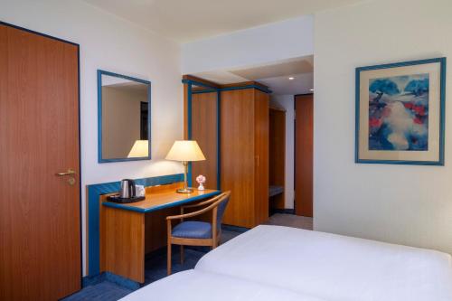 a hotel room with a bed and a desk at Wyndham Garden Wismar in Wismar