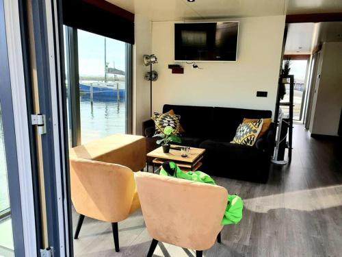 un soggiorno con un divano, un tavolo e delle sedie di Houseboat Isola a Monnickendam
