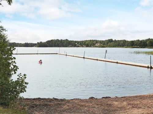 a person is in the water near a dock at 4 star holiday home in Unnaryd in Unnaryd