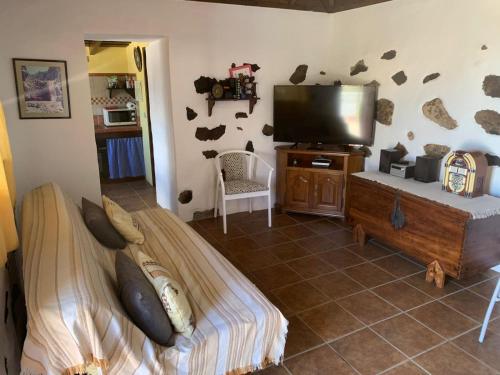 Un dormitorio con una cama y un televisor de pantalla plana. en Casa El Pajero, en Breña Alta