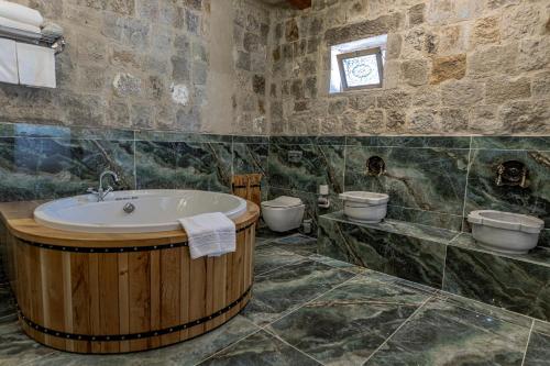 a bathroom with a large tub and two toilets at Göreme Cave Suites in Goreme