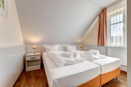 a bedroom with a bed with white sheets and a window at Küstenhaus Koserow in Koserow