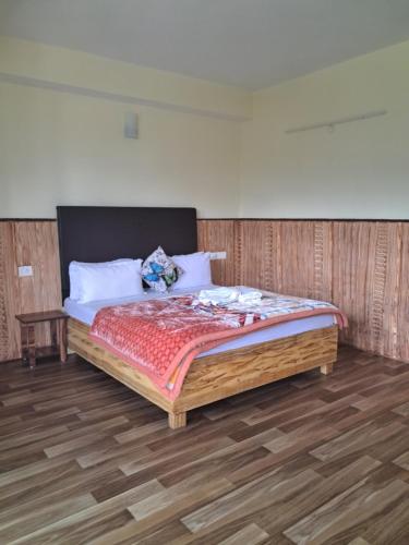 a bedroom with a large bed with a wooden floor at KHI GHA THANG Homestay in Pelling