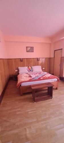 a bedroom with a bed and a table in it at KHI GHA THANG Homestay in Pelling