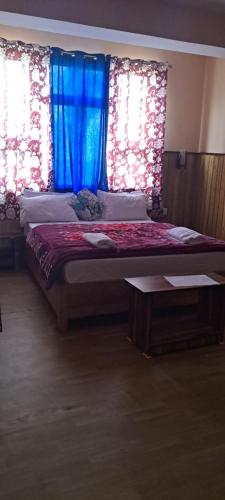 a bedroom with a large bed with blue curtains at KHI GHA THANG Homestay in Pelling